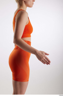 Unaisa  1 arm dressed flexing orange sports bra side…